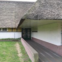 School, Hilversum. Dudok seemed unafraid of trying various langauges and materials. This school is entirely roofed with thatch. Dudok manages to produce a canopied entry by sweeping the roof over the entry path. Note low wall and paving.